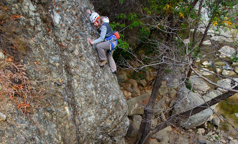 Female rock climber making her way up a steep rock face in the Santa Barbara backcountry