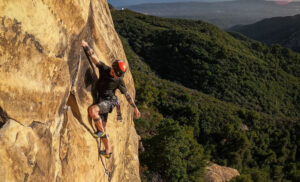 Alex Bury clings to a steep rock face overlooking the ocean in Santa Barbara