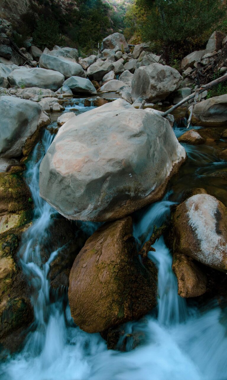 Mountain creek flowing over large sandstone boulders in a shaded canyon near Santa Barbara.