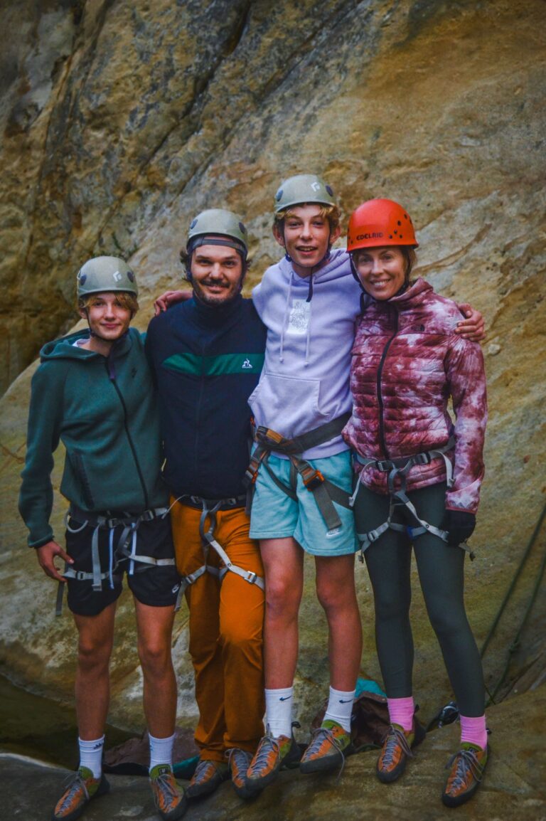 Family posing together after a guided rock climbing session in Santa Barbara, wearing helmets and harnesses on local sandstone cliffs.