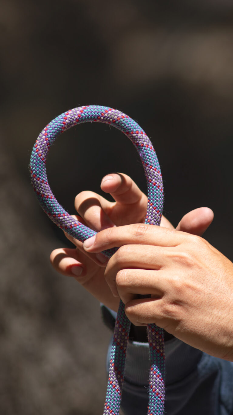 Hands forming a bight in a climbing rope during knot-tying instruction in a single-pitch course.