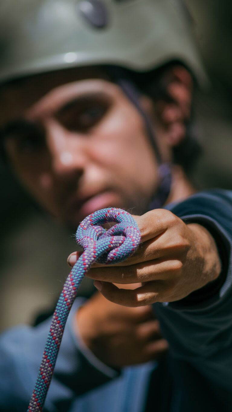 Climber holding a rope and practicing a knot during a rock climbing instruction course in Santa Barbara.