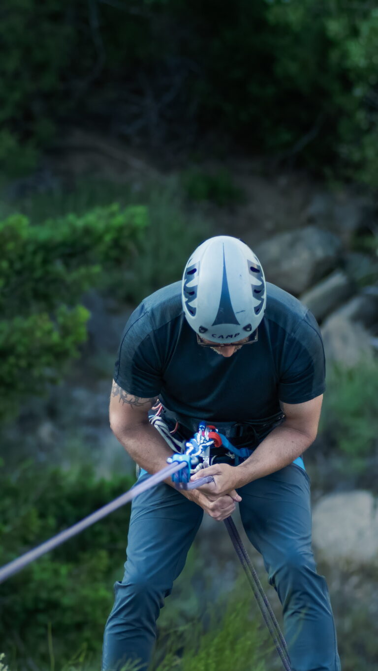 Man wearing a helmet and harness practicing a controlled rappel during a single-pitch climbing instruction session in Santa Barbara.